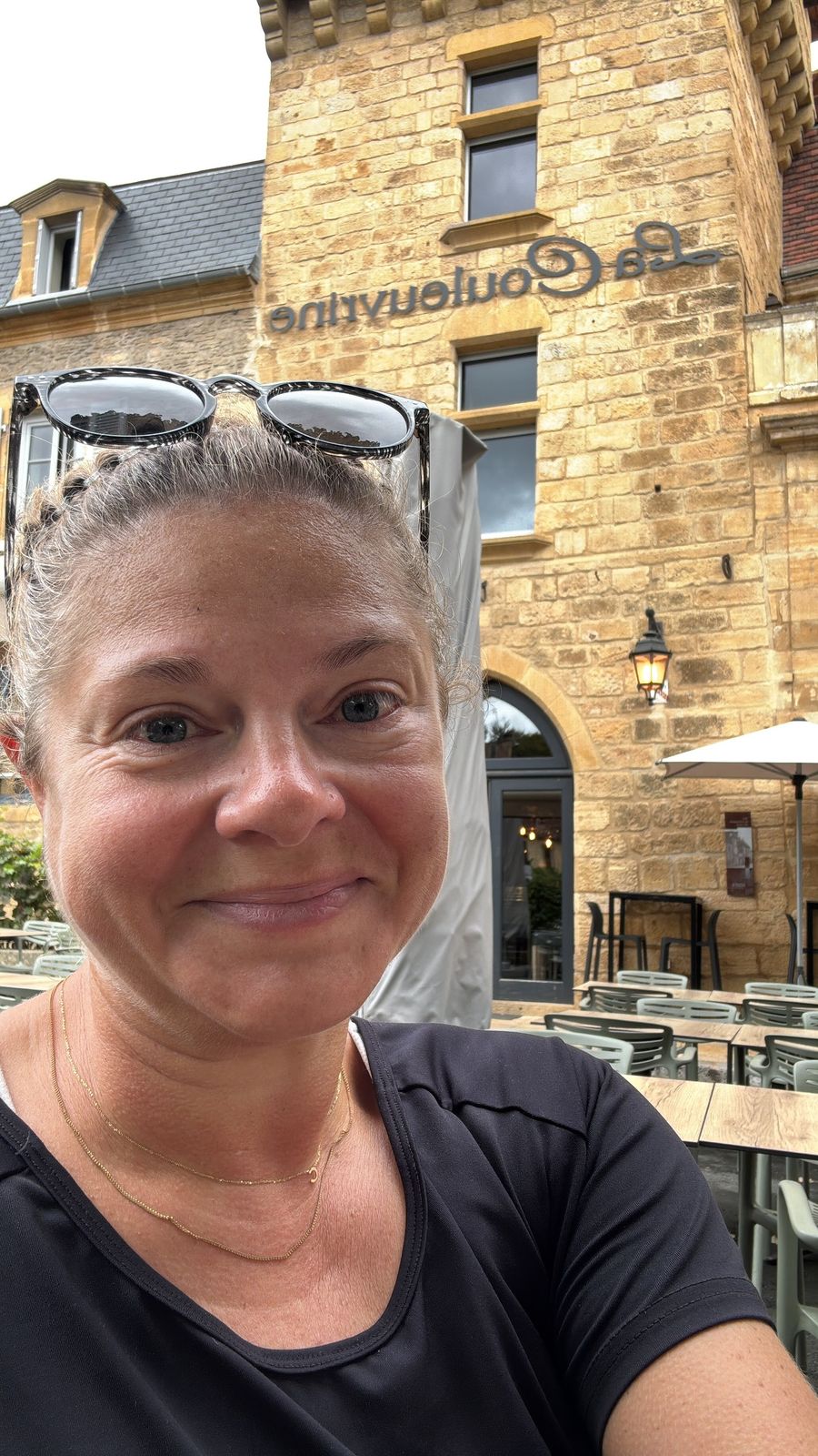 Cassie smiling outside the golden-stone Hôtel La Couleuvrine in Sarlat