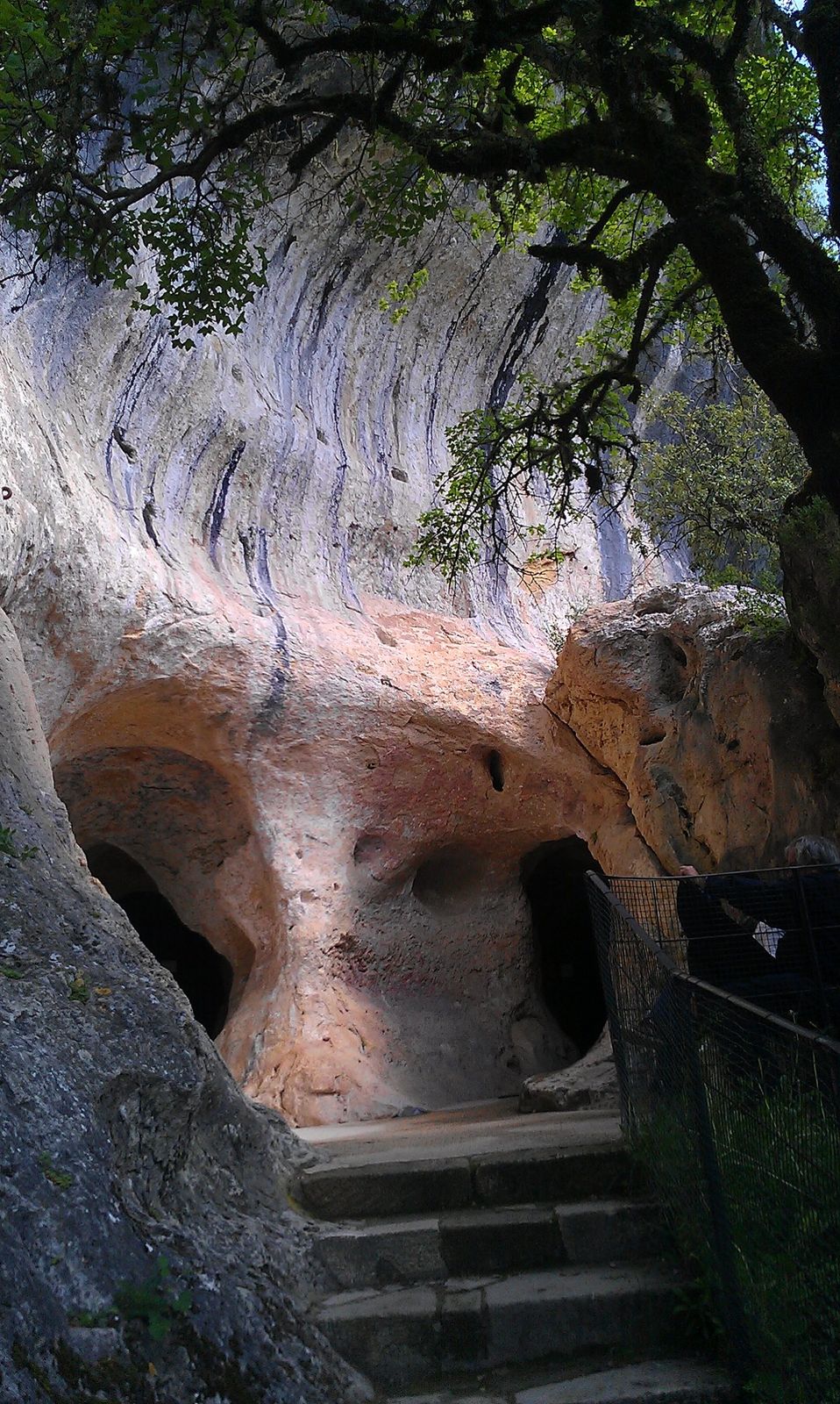 Stone steps climbing beneath an overhanging cliff to the entrance of the Font-de-Gaume cave