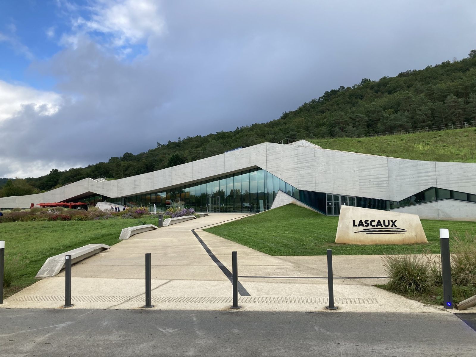 A long, low modern building set into a green hillside, with a path leading to the Lascaux IV entrance