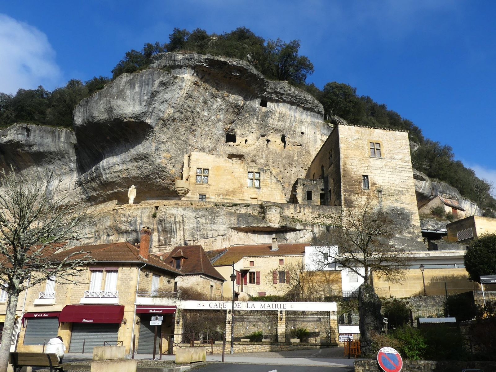 A limestone cliff above the rooftops of Les Eyzies, with the museum building set into it