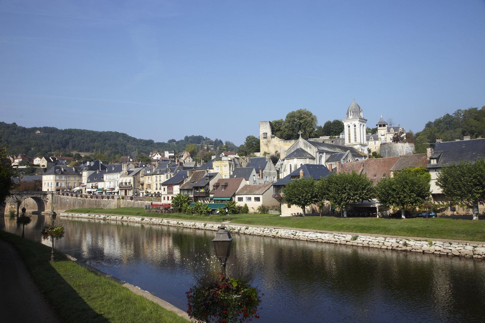The town of Montignac across the calm Vézère river under a blue sky