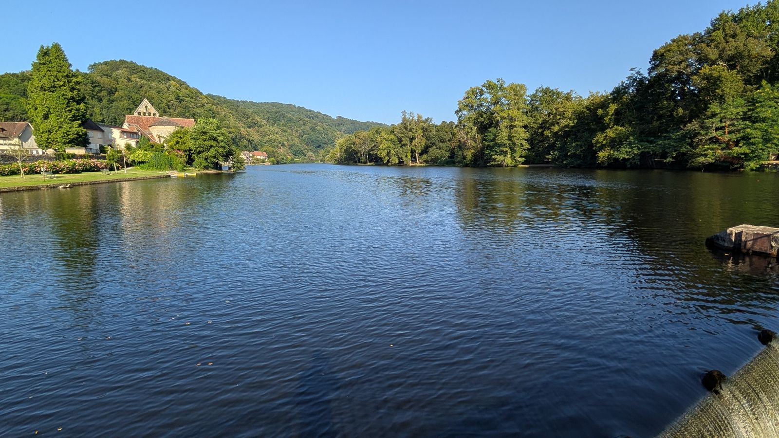 The calm Dordogne with wooded hills and riverside houses at Beaulieu-sur-Dordogne