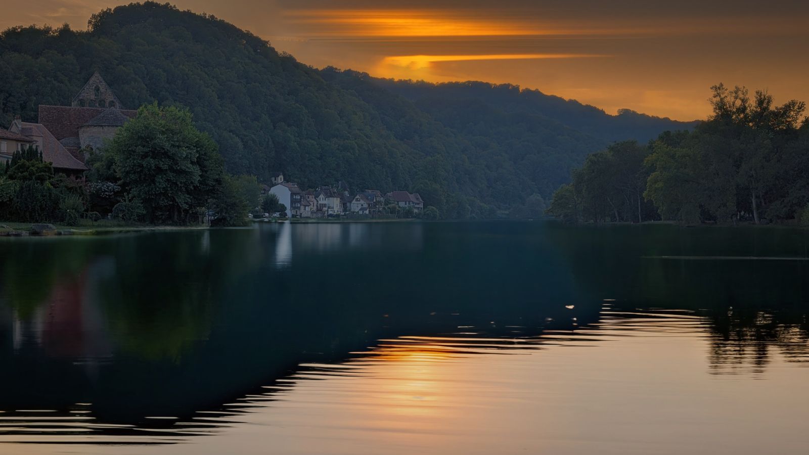 Sunset over the Dordogne at Beaulieu-sur-Dordogne, the village and hills reflected in the river