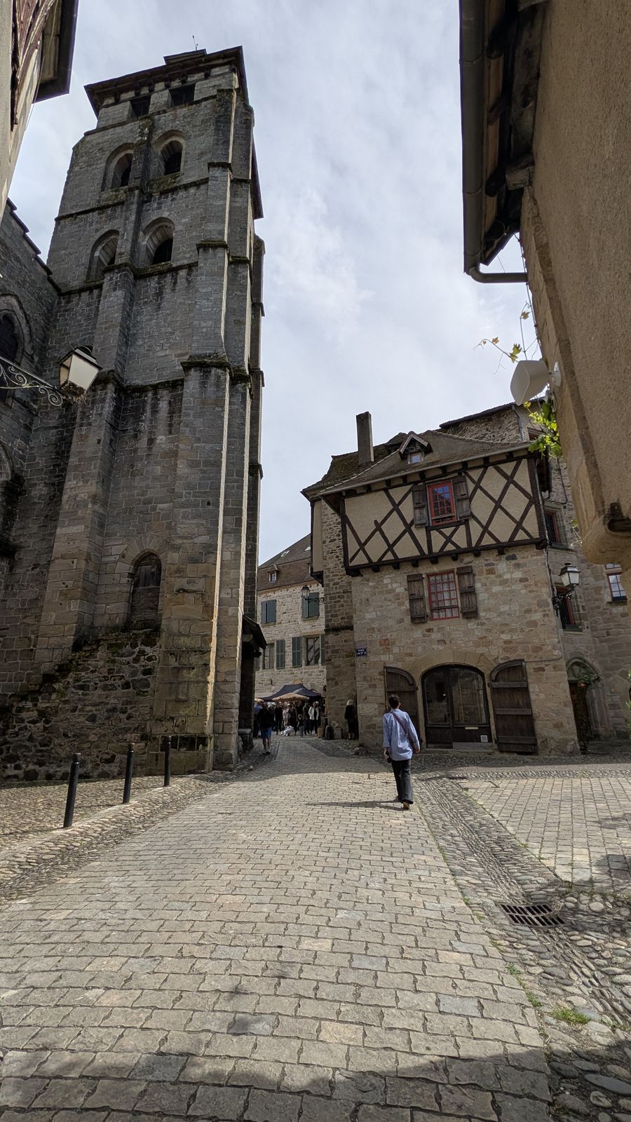 A tall stone tower and a half-timbered house on a cobbled street in Beaulieu-sur-Dordogne
