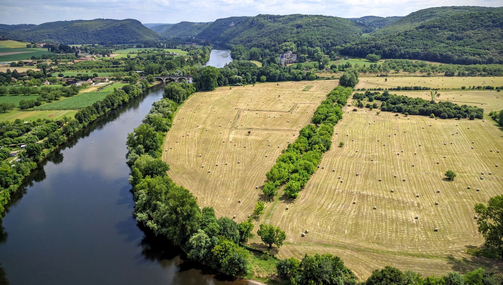 A wide bend of the Dordogne between golden fields, seen from the walls of the Château de Beynac