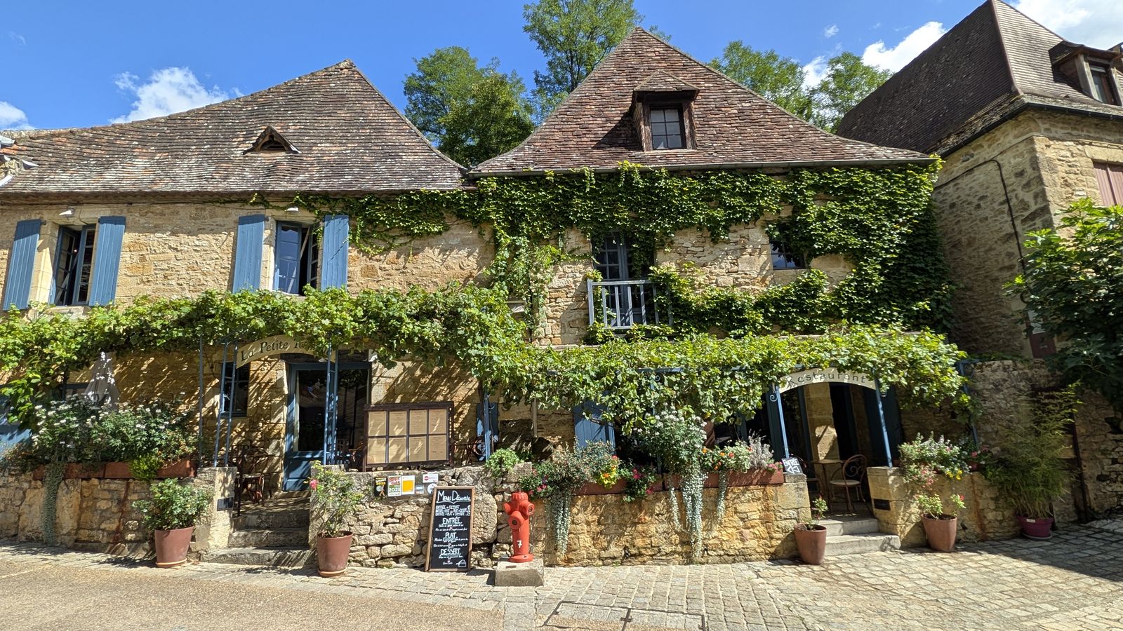 Ivy-covered stone houses with blue shutters in Beynac