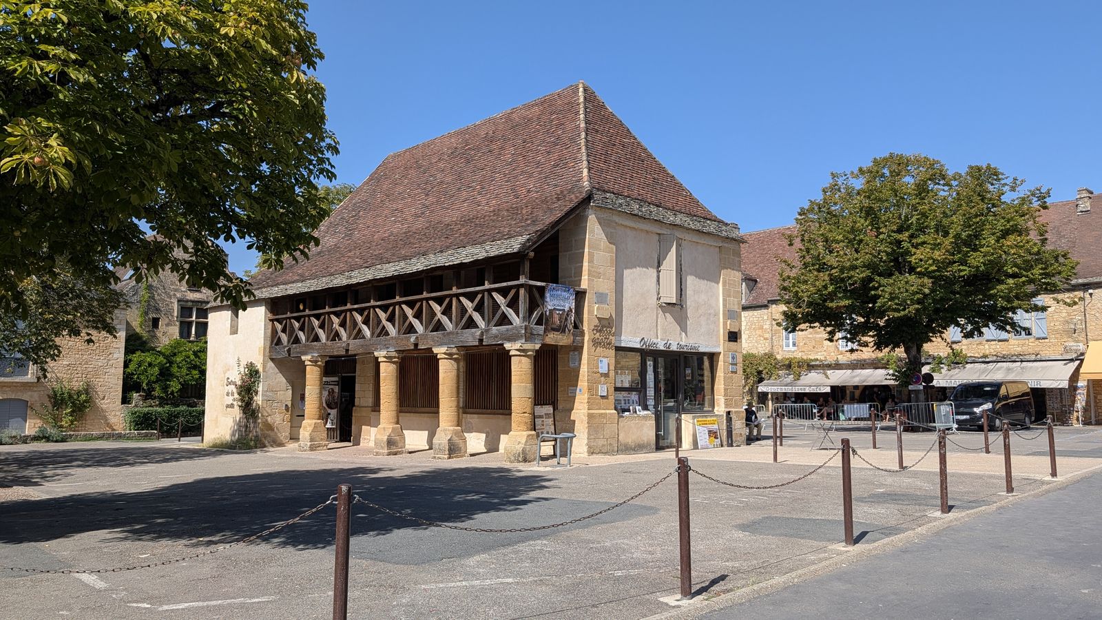 A stone market hall with a tiled roof on a square in Domme