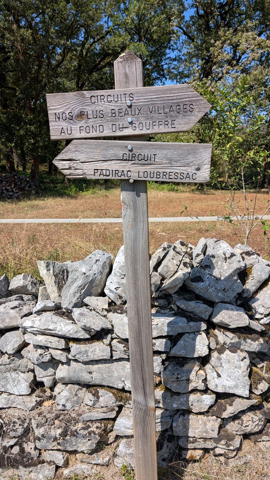 Wooden walking signposts above a dry-stone wall near Loubressac