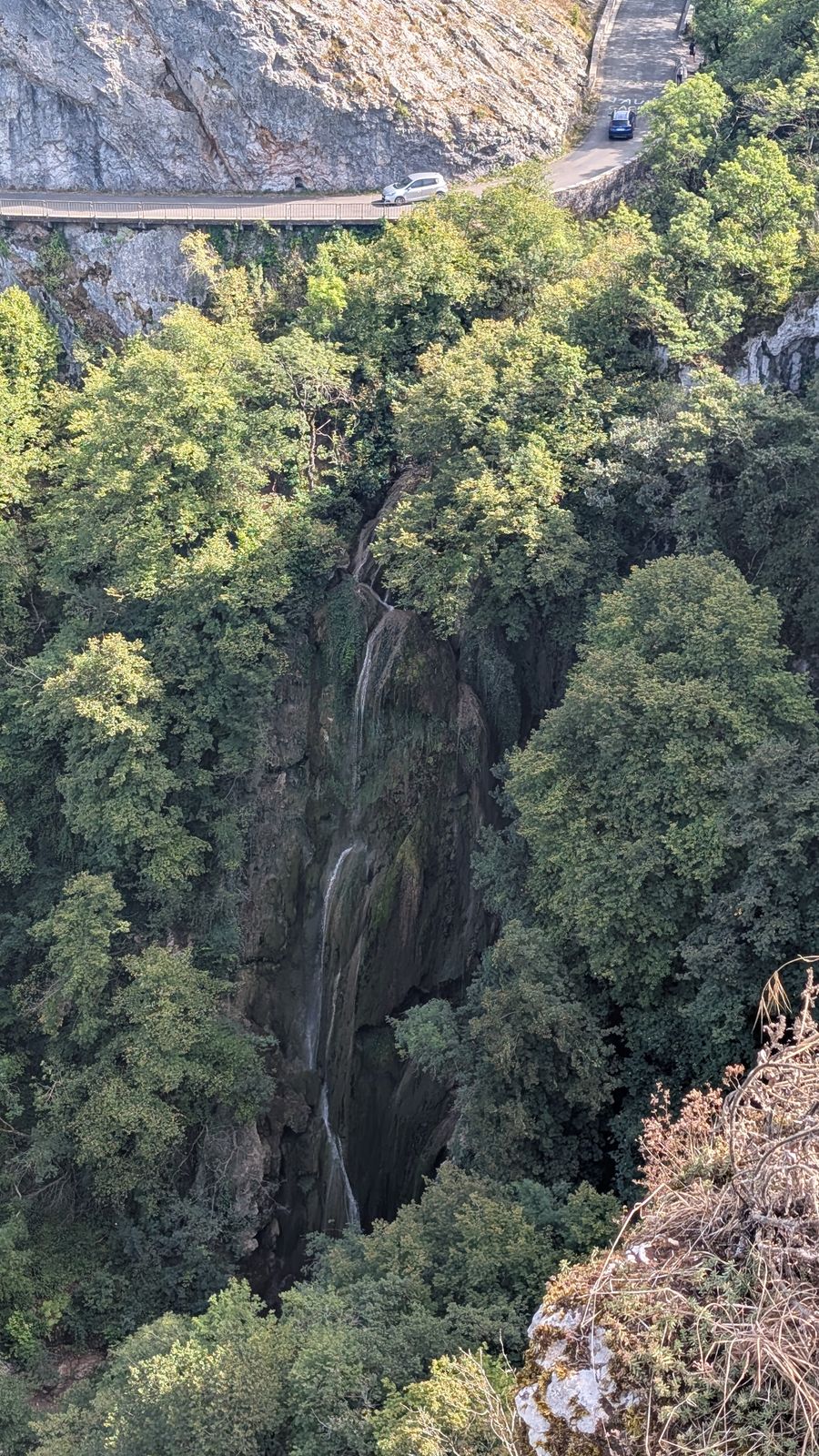A waterfall falling through dense woods in a rocky gorge, seen from the clifftop above Autoire