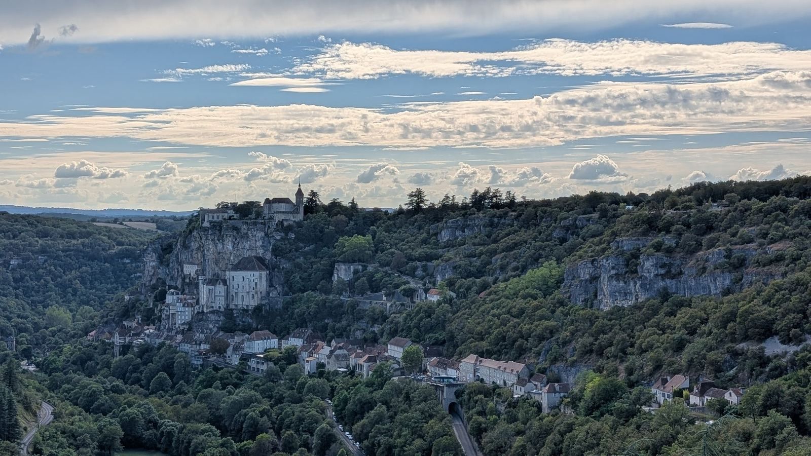 The village of Rocamadour clinging to its cliff above a green valley