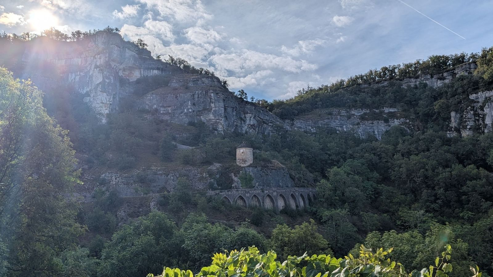 Sunlit limestone cliffs above a wooded canyon at Rocamadour