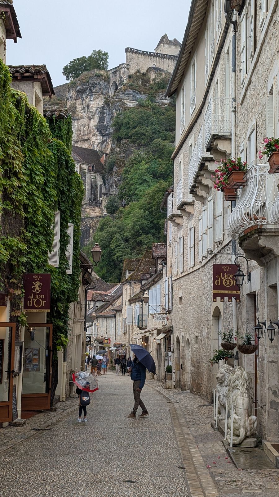 A narrow village street lined with stone houses, with the cliff above, Rocamadour