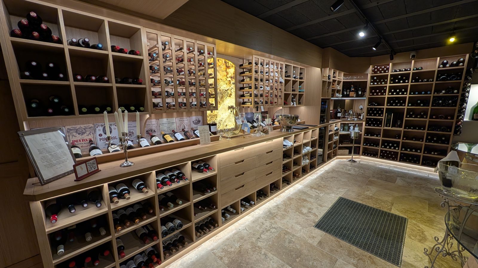The wine racks and lit stone panel of the cellar at Aux 3 Sens, Sarlat