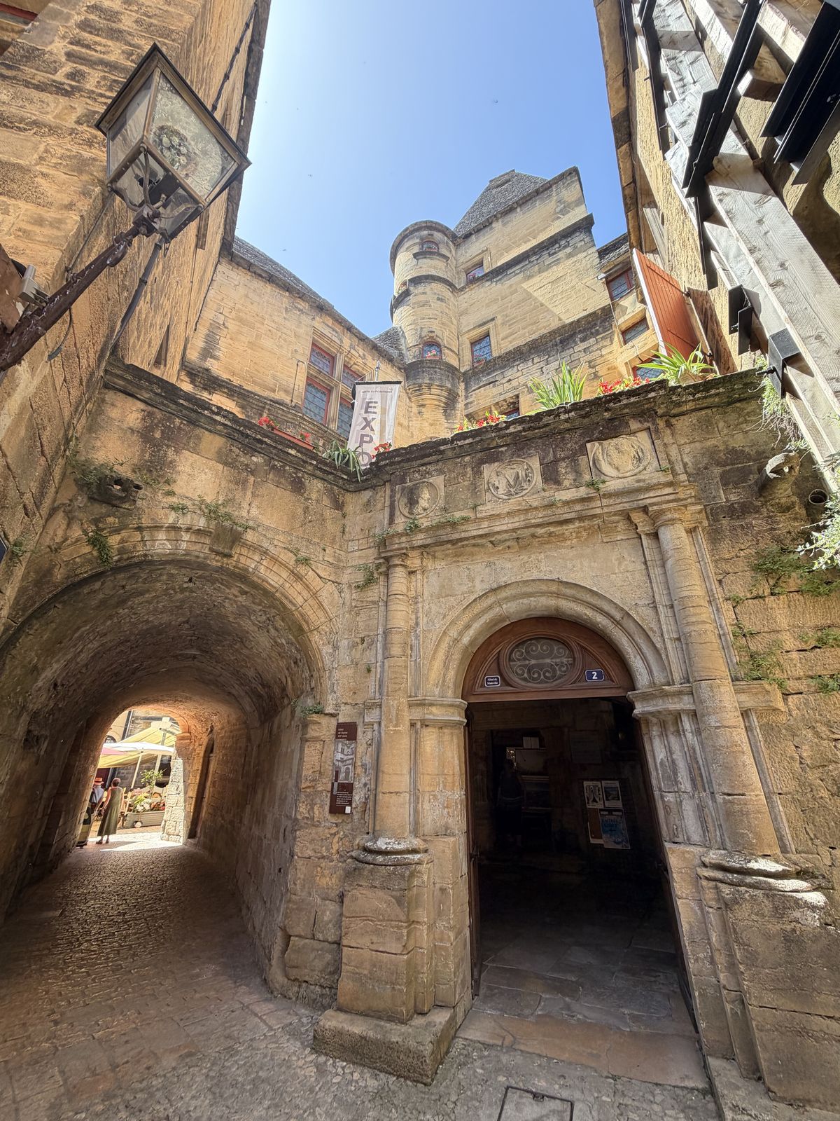 Golden stone arches and a stair tower around a courtyard in Sarlat