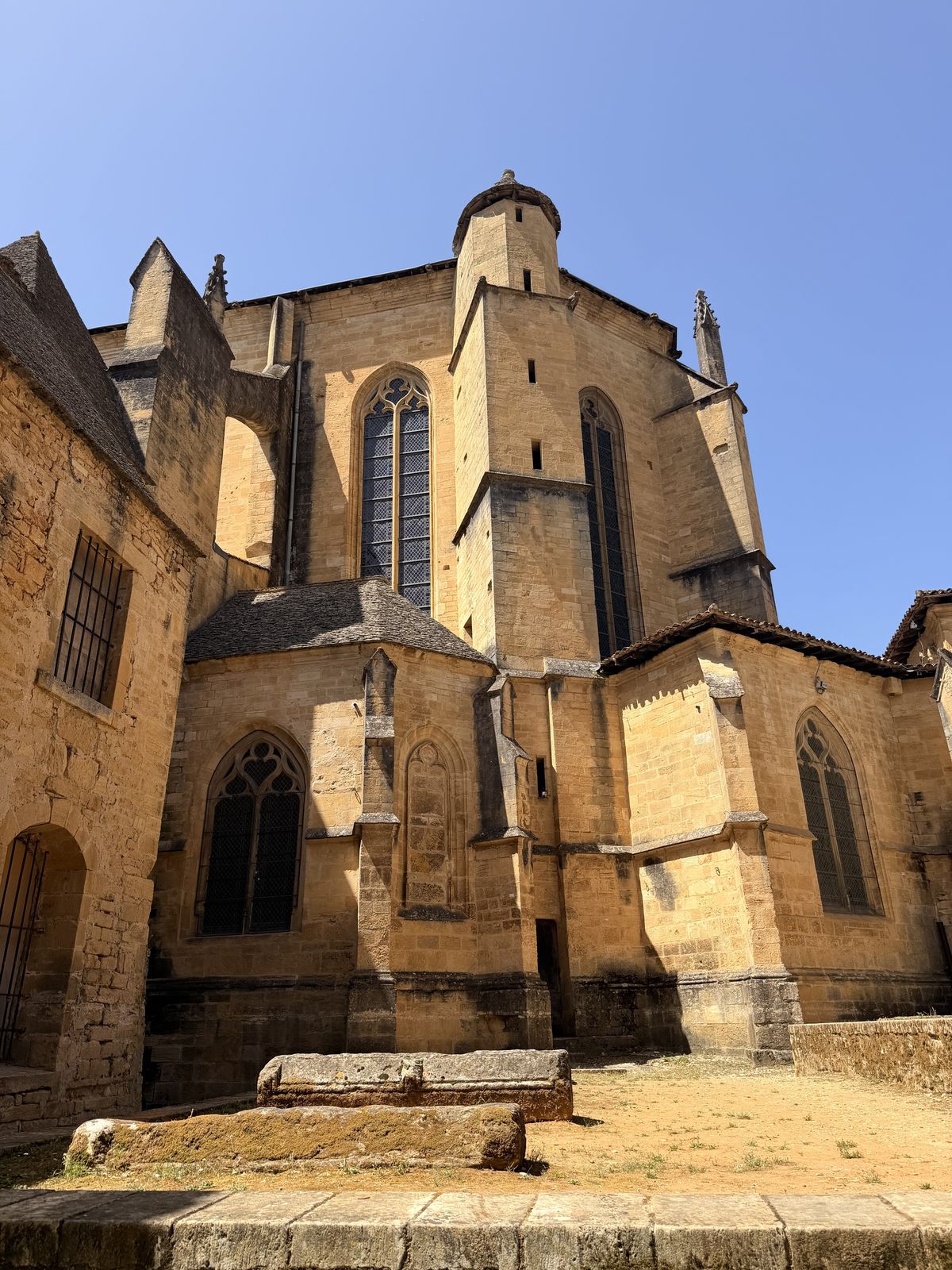 The stone apse and buttresses of Sarlat Cathedral under a blue sky