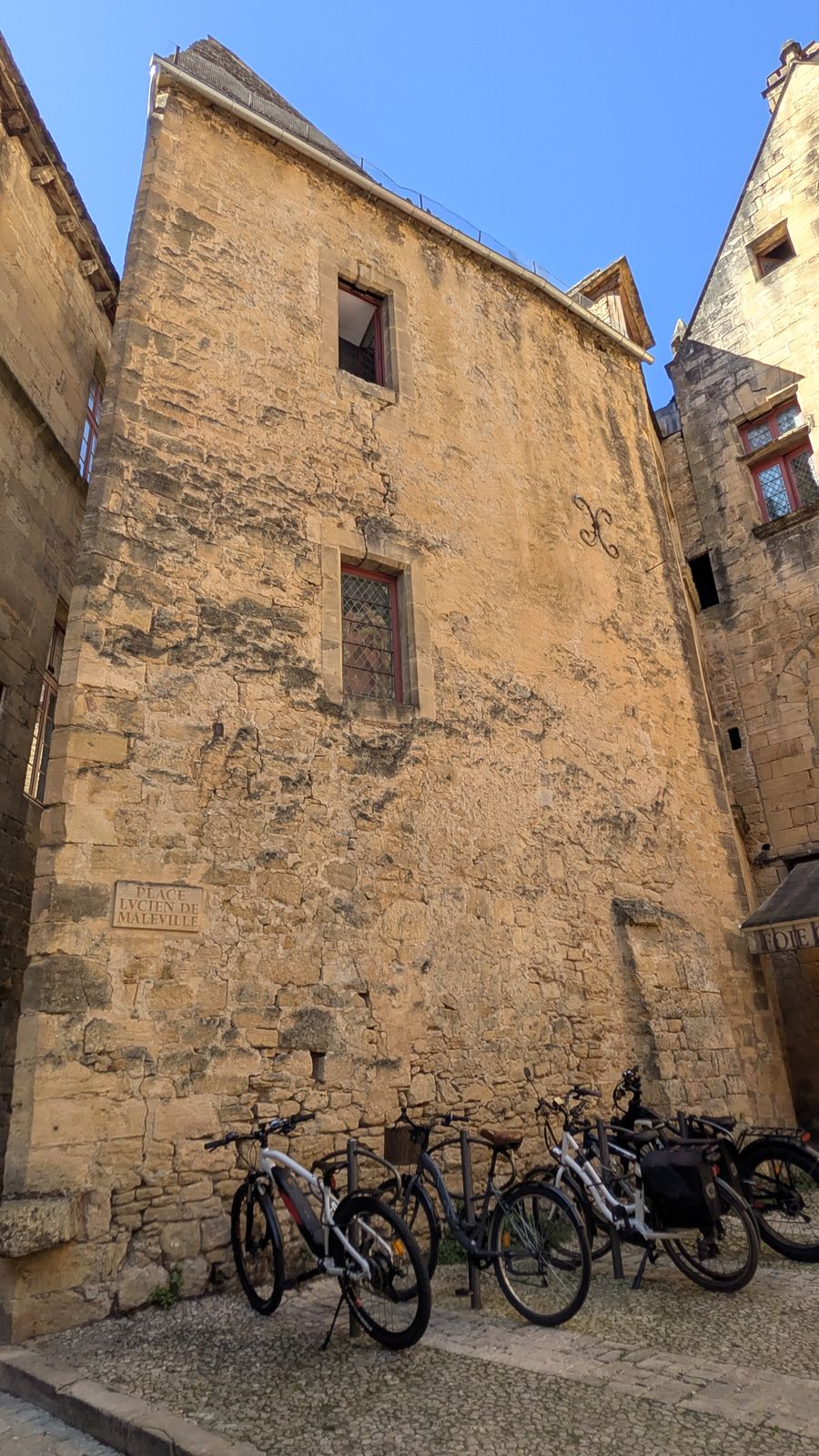 Bicycles parked against the foot of a tall golden-stone house in Sarlat