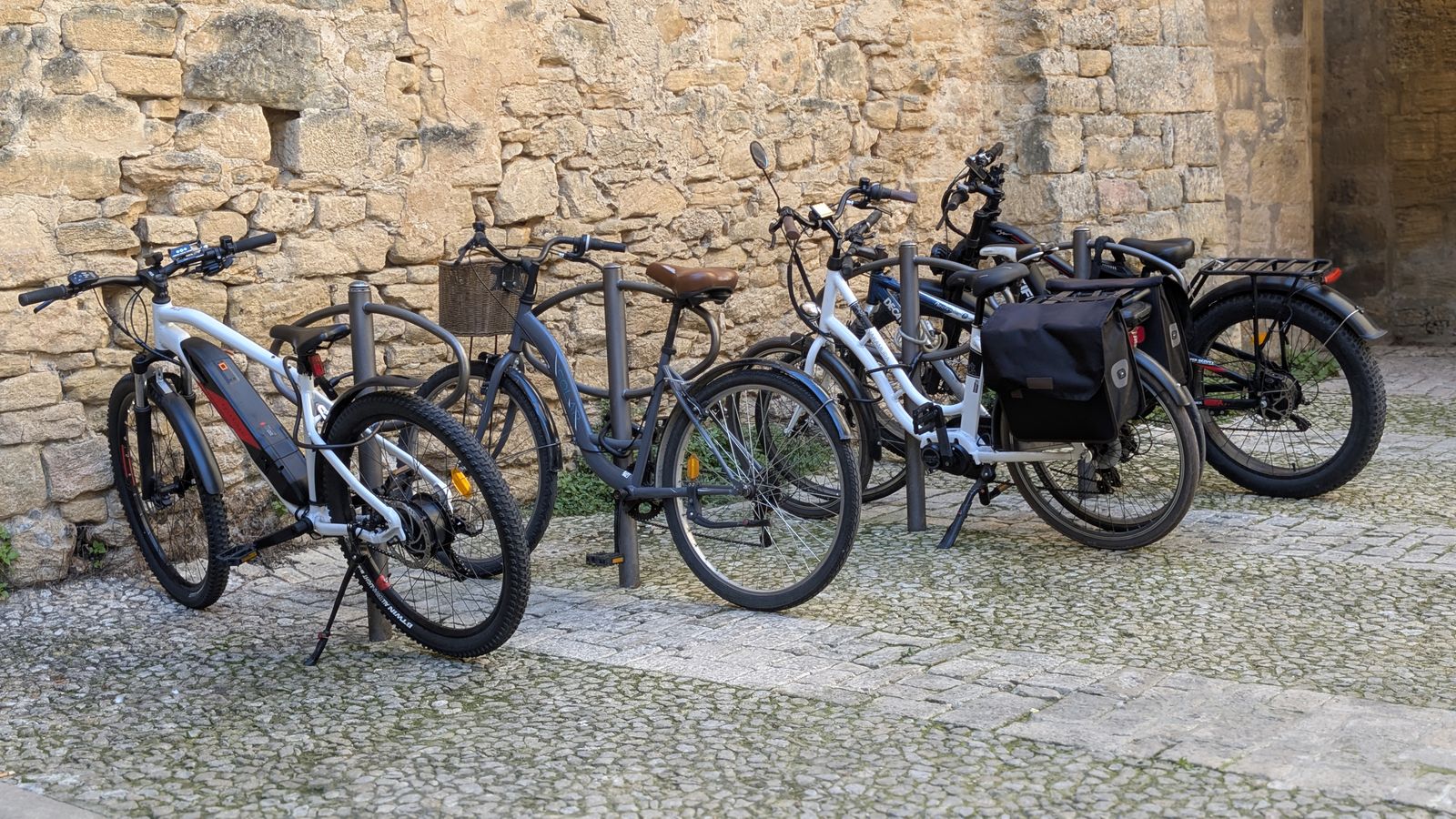 Bikes and e-bikes parked against an old stone wall in Sarlat