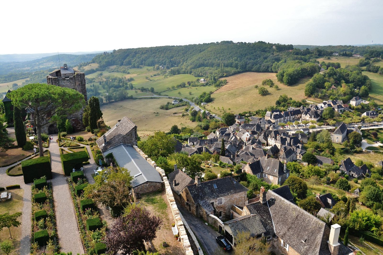 The slate rooftops of Turenne below its castle keep, with green hills beyond
