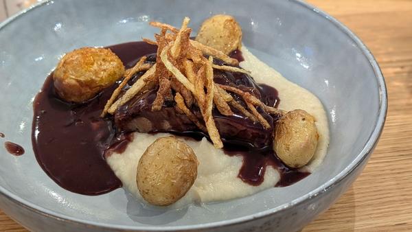 Beef in a rich red wine sauce on creamy mash, with crispy potato straws