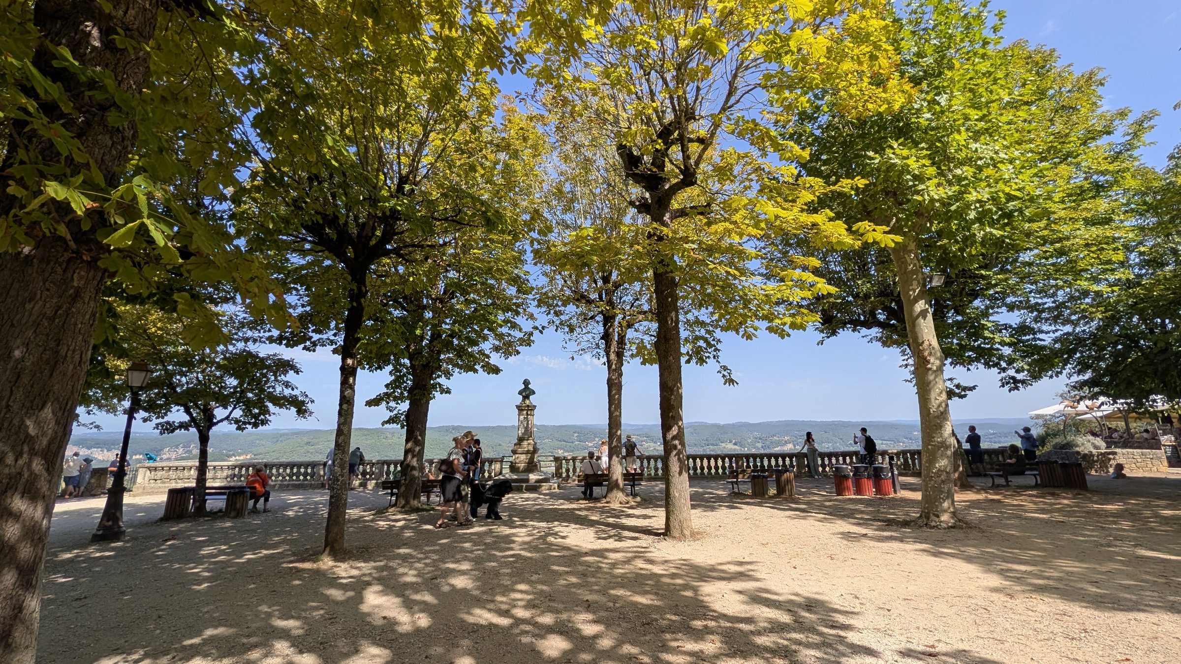 Visitors on the shaded clifftop promenade at Domme, above the Dordogne valley